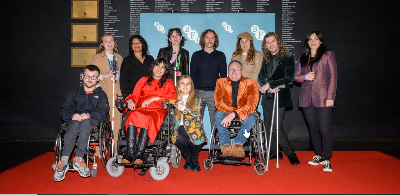 A group of people gather on a red carpet infront of a BFI screen.