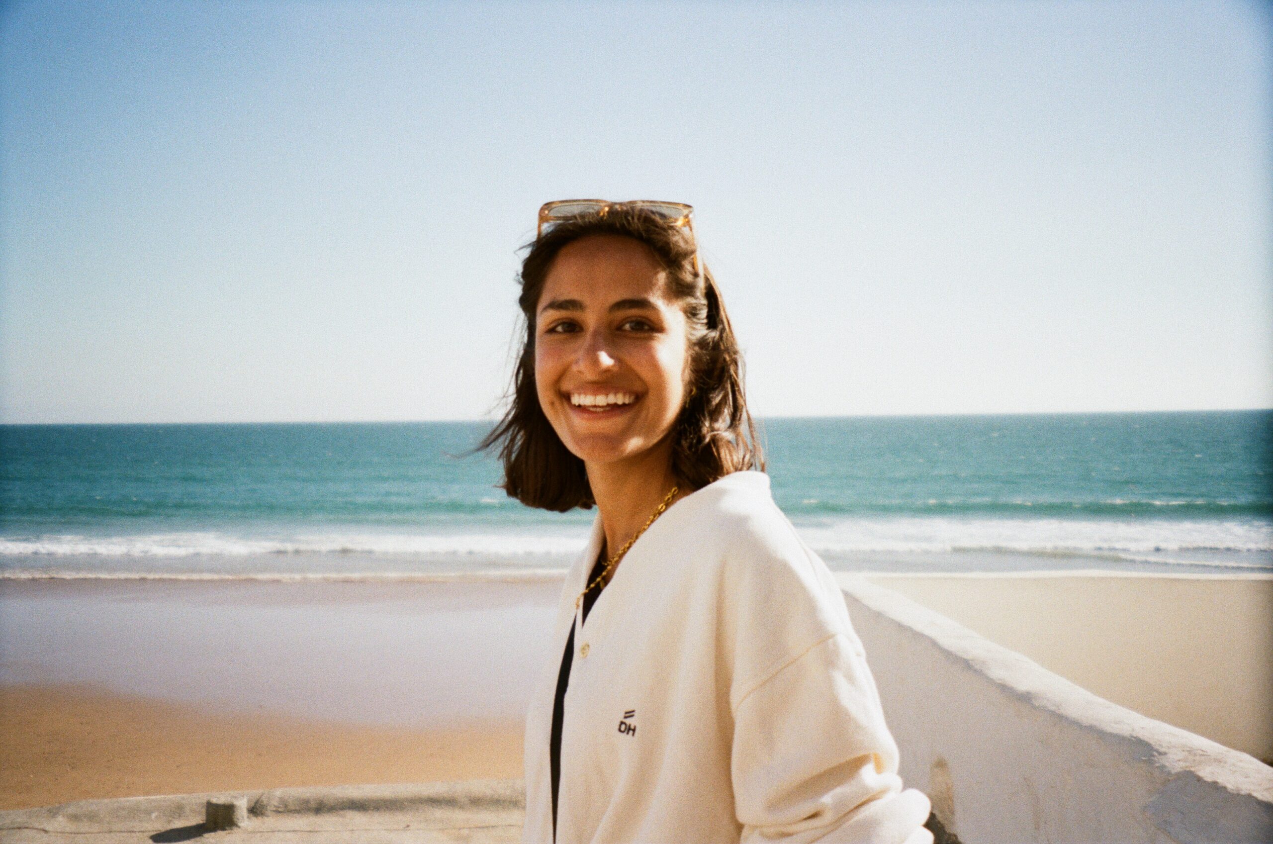Headshot of myself standing and smiling, I have short brown hair and brown skin