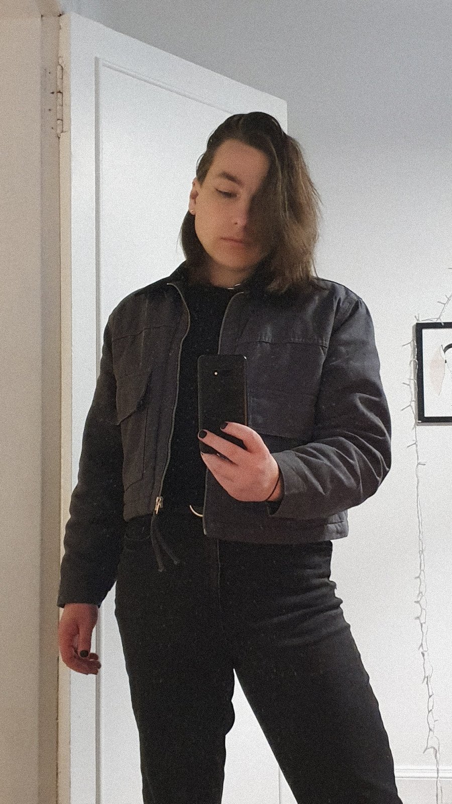 Selfie style portrait of Kal Corke. Transfeminine nonbinary individual phone in hand reflected in a mirror