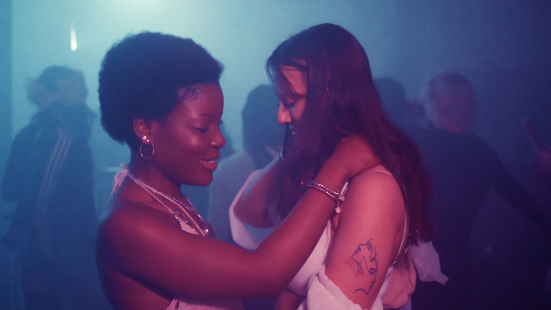 Two people embrace each other in a hazy nightclub environment.