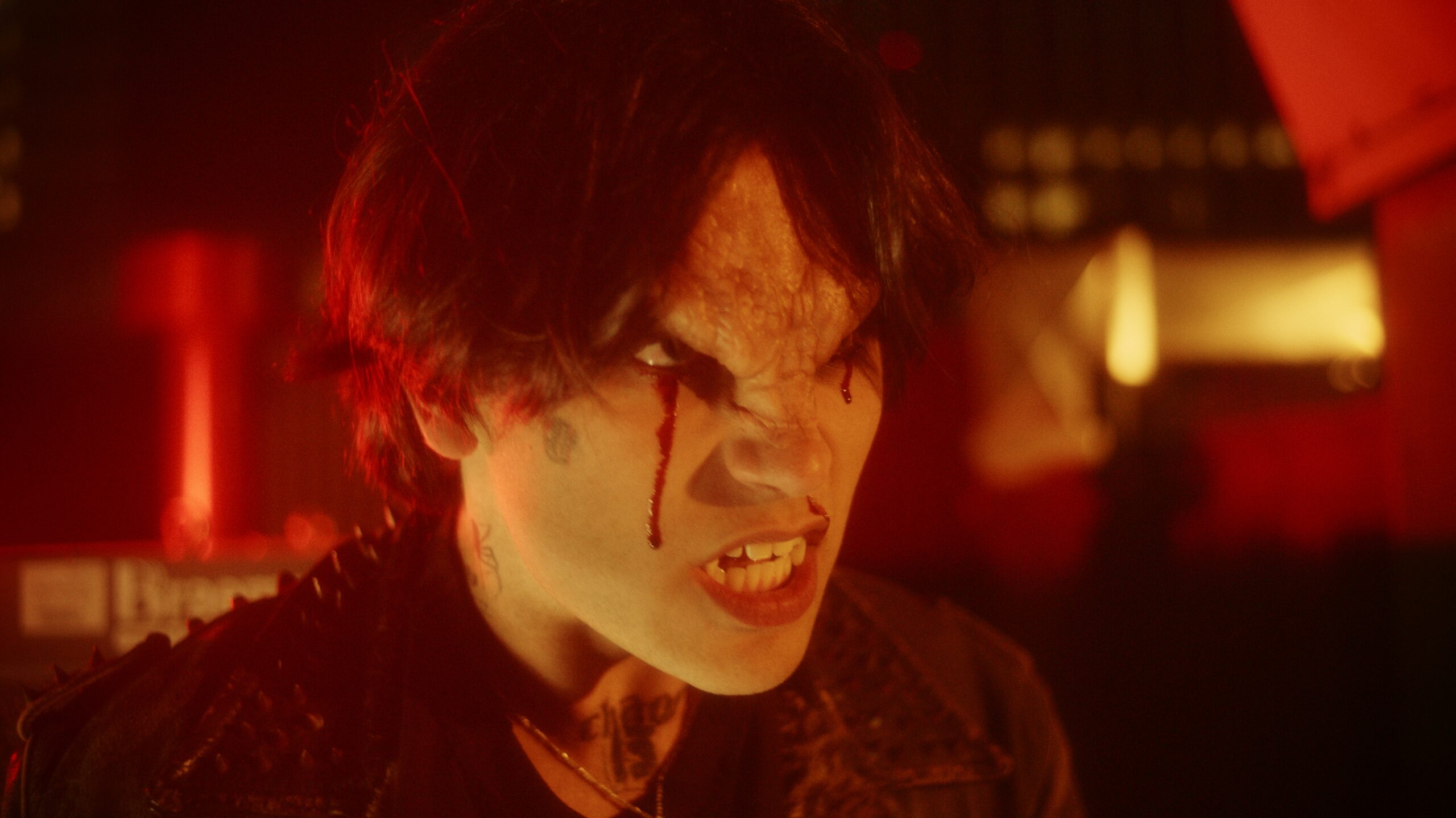 A demon-like being with fangs and bleeding eyes growls amongst a hazy red background.