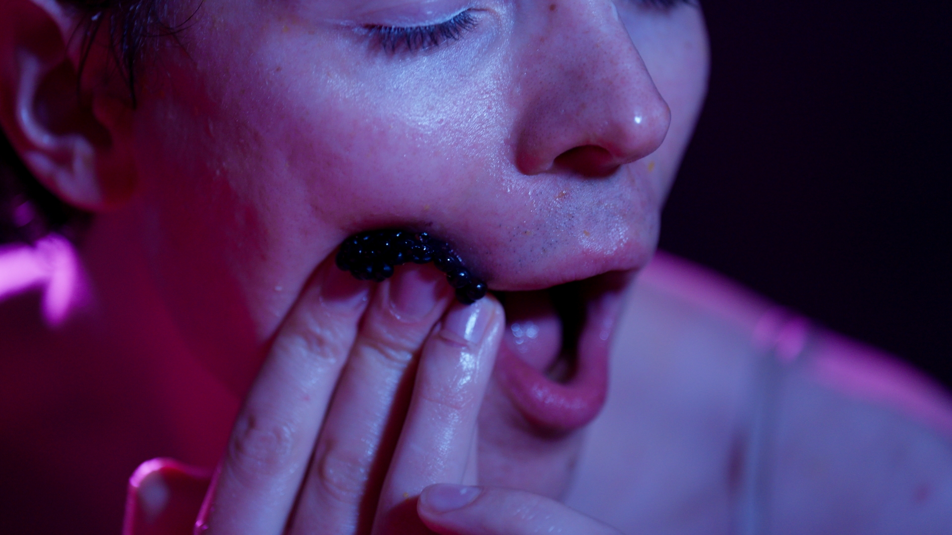 WORM Choice 1 A berry is pressed into the cheek of an open-mouthed white person.