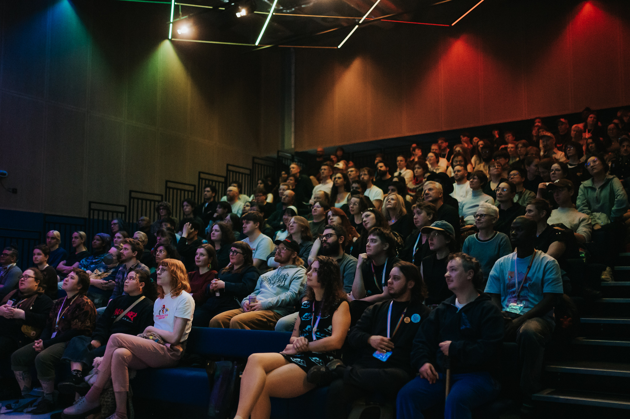 A full cinema room with rainbow lighting in the background.