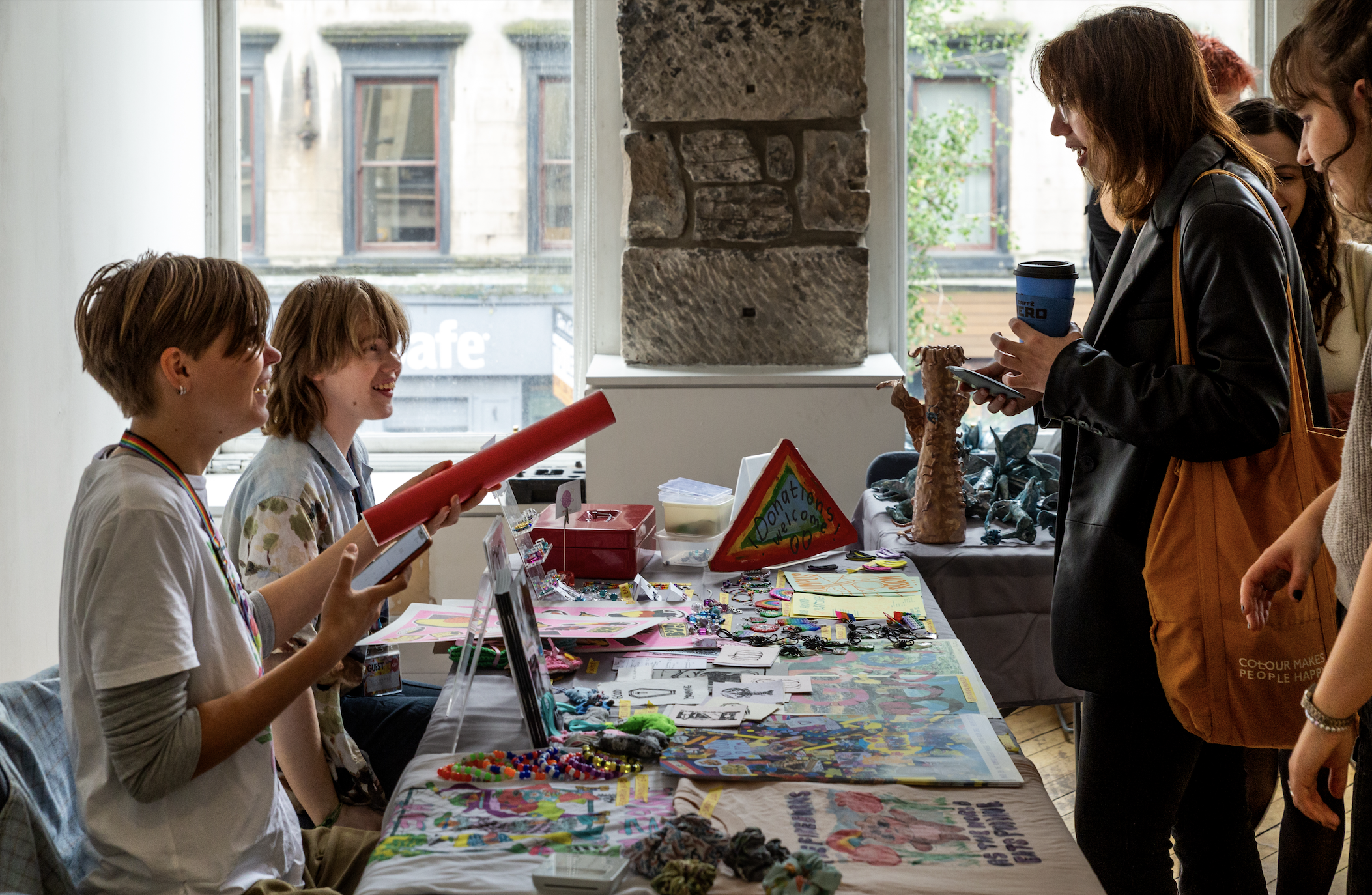 Two artists seating down selling their work in a craft fair.