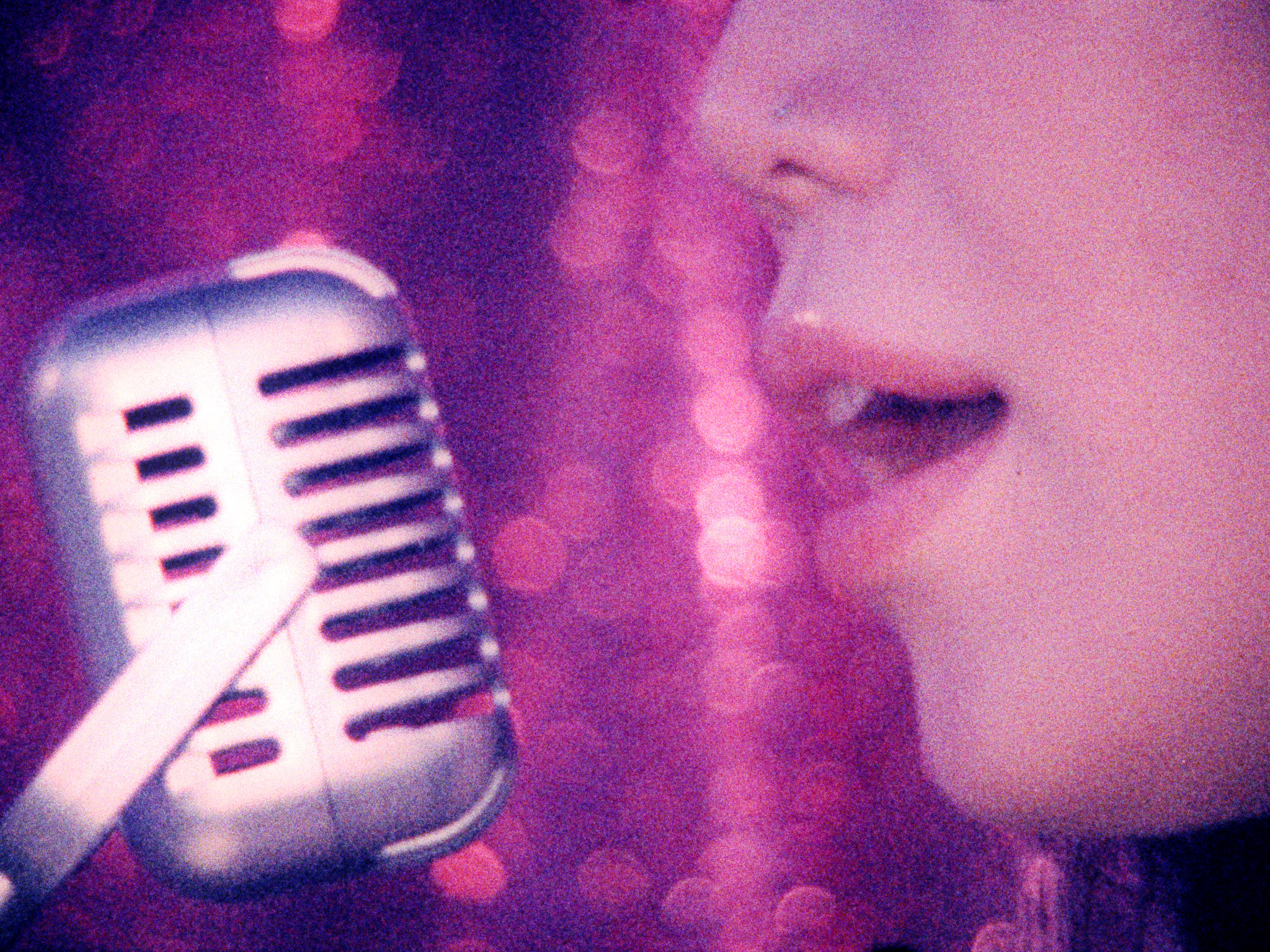 Close-up lips singing into vintage microphone against sparkly pink backdrop.
